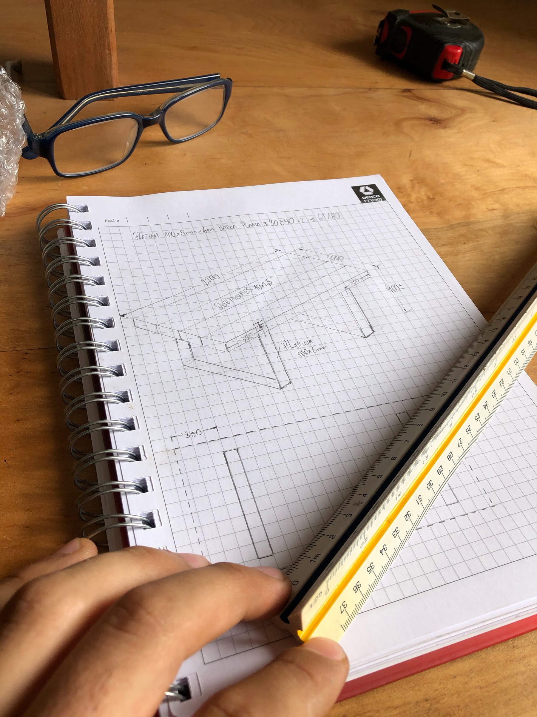 Croquis tecnico realizado a mano junto a una regla y herramientas de medicion